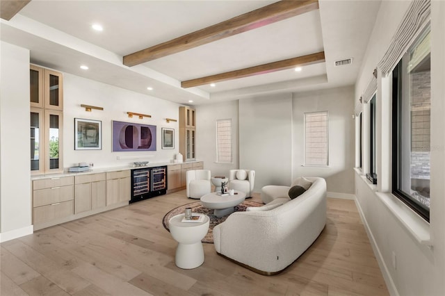 living room with beam ceiling, baseboards, light wood-type flooring, and visible vents