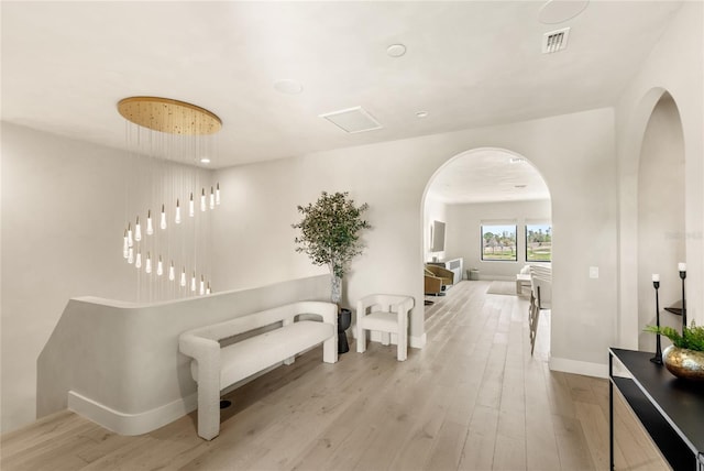 corridor with visible vents, wood finished floors, arched walkways, and baseboards