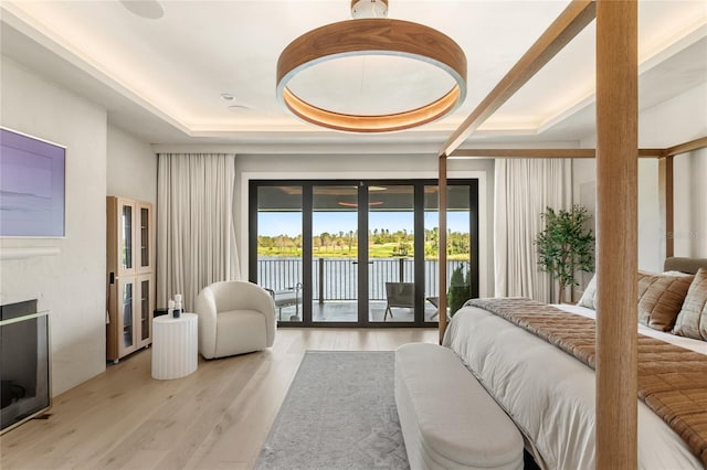 bedroom featuring access to exterior, light wood-style floors, and a water view