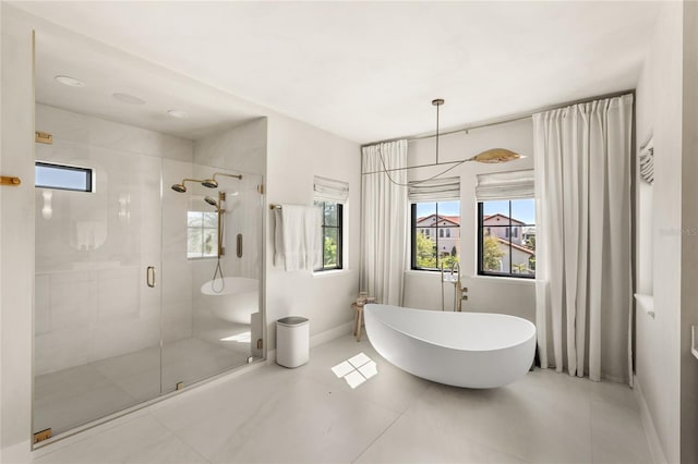 full bathroom featuring tile patterned flooring, a stall shower, a freestanding bath, and baseboards