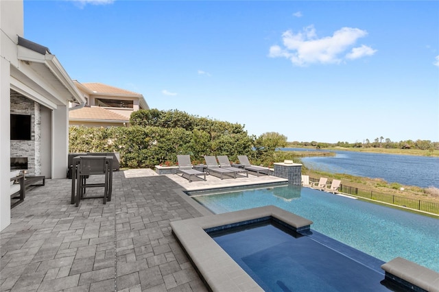 view of pool featuring an in ground hot tub, a water view, and a patio