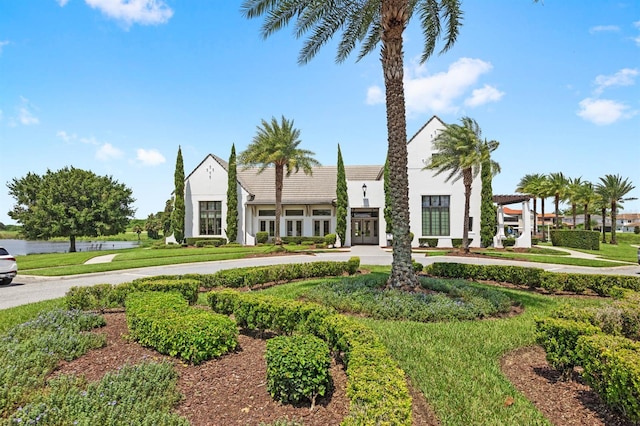 view of front of house with stucco siding, a tile roof, and a front lawn