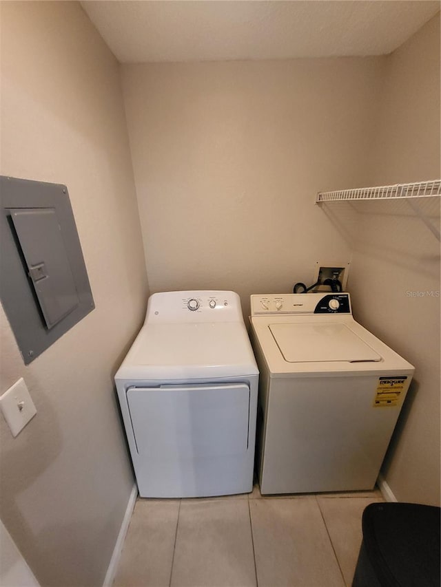 washroom featuring baseboards, electric panel, laundry area, light tile patterned floors, and independent washer and dryer