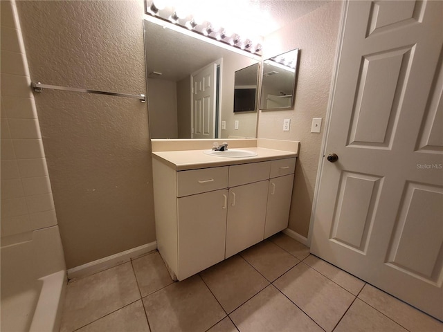 bathroom with vanity, tile patterned floors, a textured wall, and baseboards