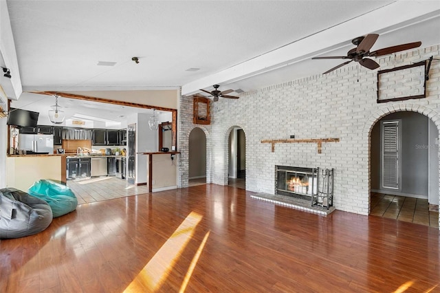 1475 Kettledrum Trl, Deltona, FL 32725 - unfurnished living room with a ceiling fan, arched walkways, a fireplace, and light wood-style flooring