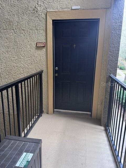 doorway to property featuring a balcony and stucco siding