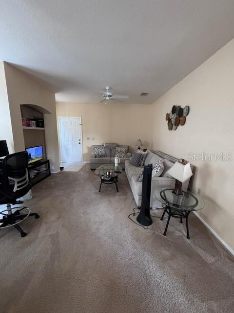 living area featuring a ceiling fan, carpet flooring, baseboards, and visible vents