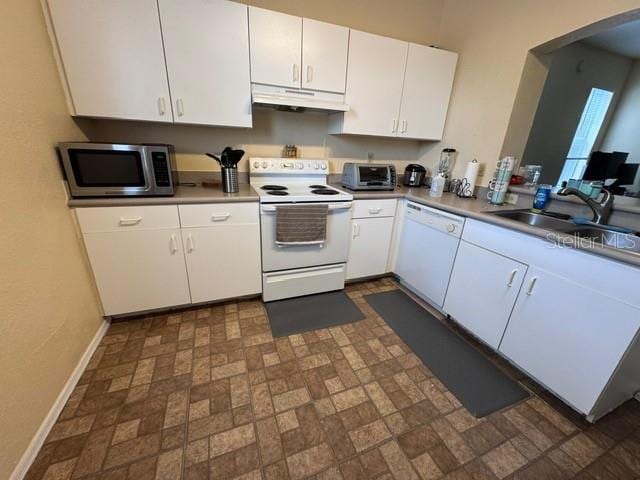 kitchen with under cabinet range hood, white appliances, white cabinetry, and a sink