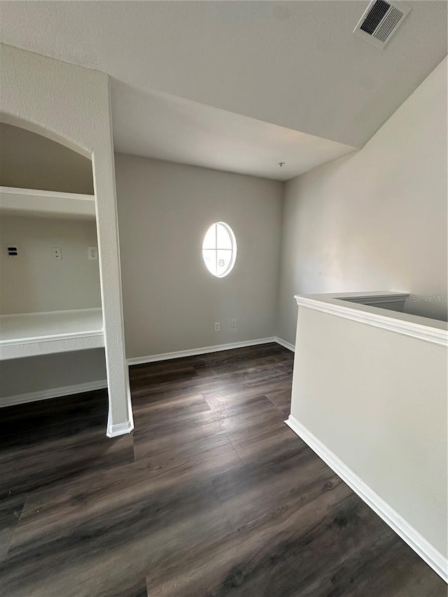 spare room featuring dark wood-style floors, visible vents, and baseboards