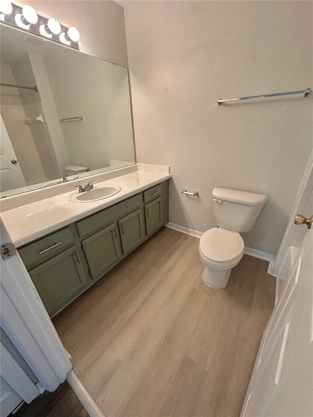 bathroom featuring vanity, wood finished floors, baseboards, a shower, and toilet