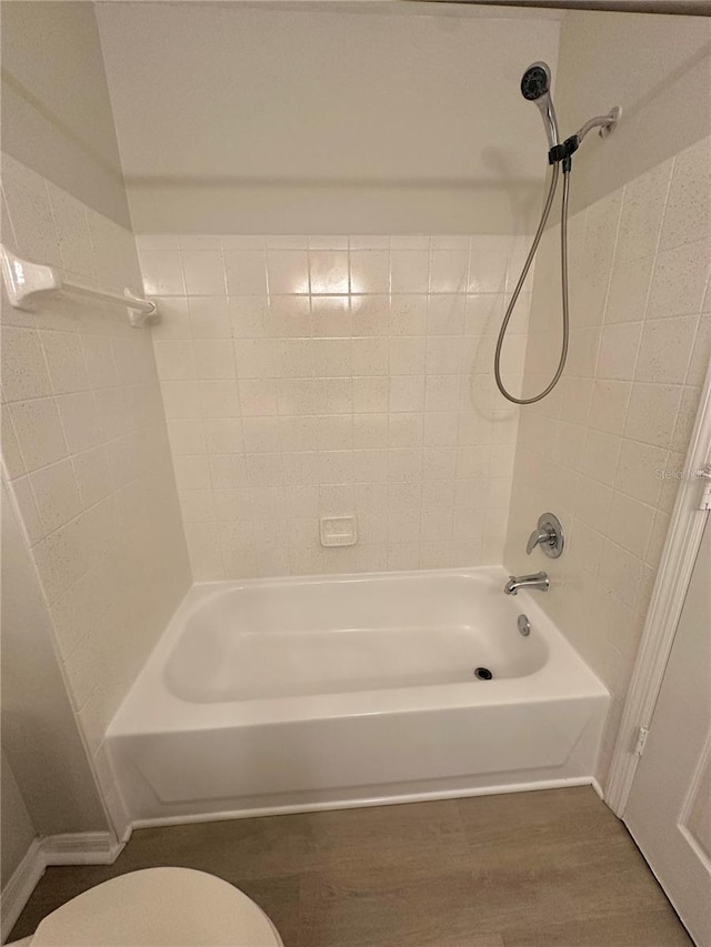 bathroom featuring toilet, wood finished floors, and shower / tub combination