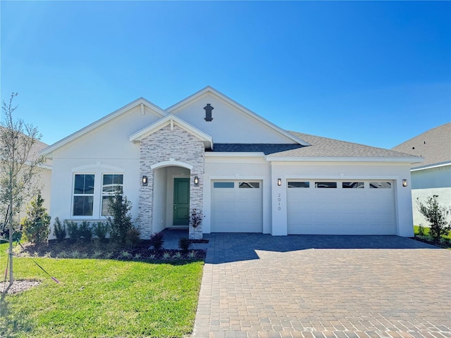 ranch-style house featuring a front lawn, decorative driveway, a garage, and stucco siding