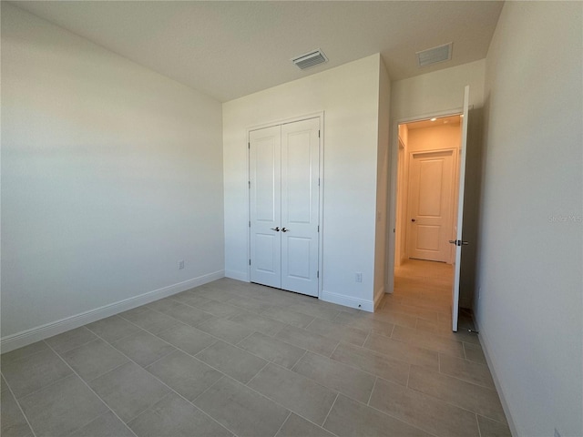 unfurnished bedroom featuring baseboards, visible vents, and a closet