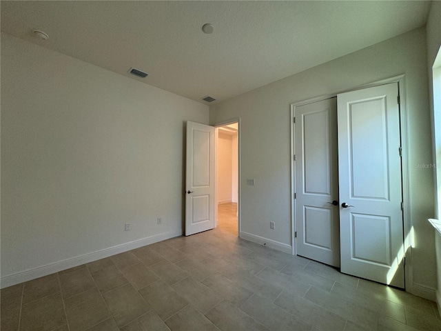 unfurnished bedroom with a closet, visible vents, and baseboards