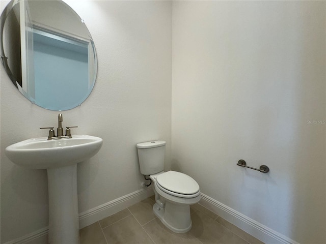 bathroom featuring tile patterned floors, baseboards, toilet, and a sink