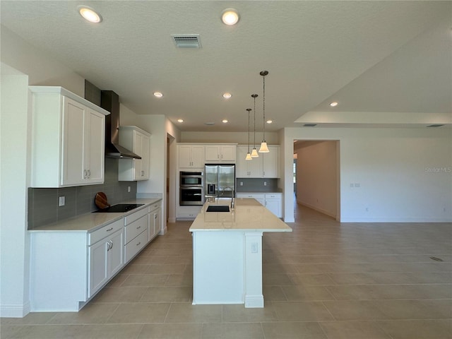 kitchen with visible vents, a sink, stainless steel appliances, white cabinetry, and wall chimney exhaust hood