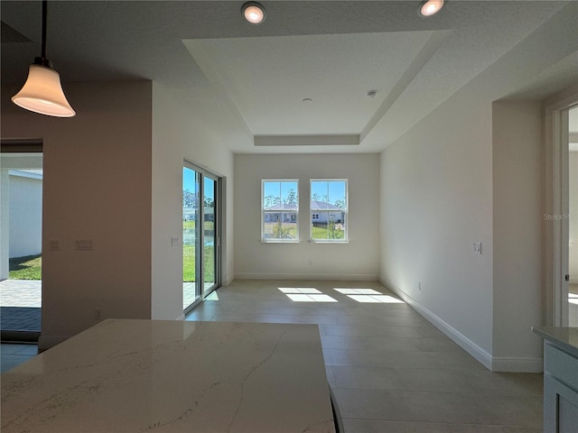 interior space featuring a tray ceiling and baseboards