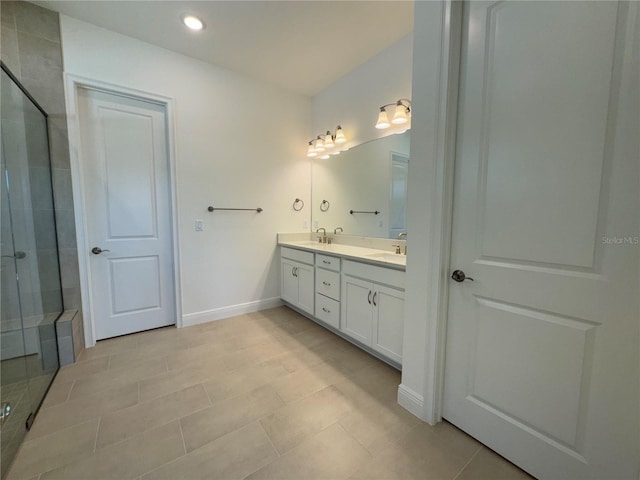 full bathroom featuring double vanity, a shower stall, baseboards, and a sink