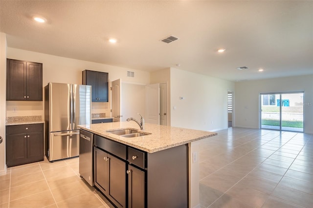 kitchen with visible vents, a center island with sink, a sink, appliances with stainless steel finishes, and light tile patterned flooring