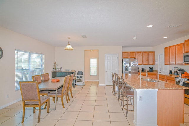 kitchen with light tile patterned floors, appliances with stainless steel finishes, a breakfast bar area, and a sink