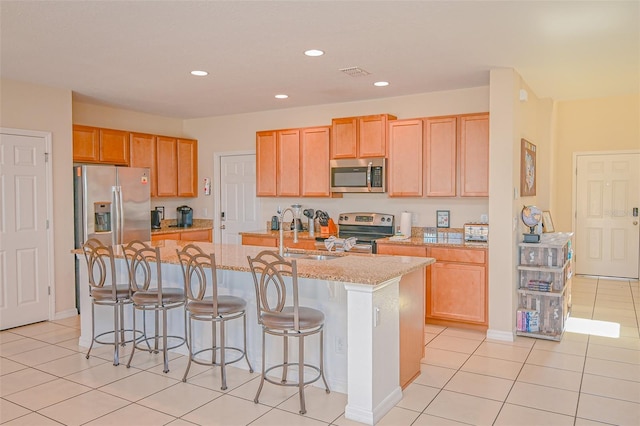 kitchen featuring light tile patterned floors, an island with sink, recessed lighting, appliances with stainless steel finishes, and a kitchen bar