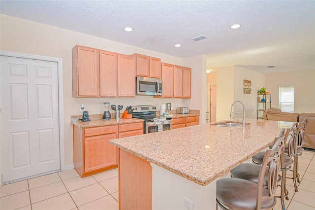 kitchen featuring a sink, appliances with stainless steel finishes, light brown cabinets, and light tile patterned floors