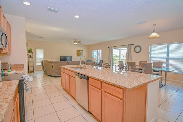 kitchen featuring light brown cabinets, open floor plan, dishwasher, light tile patterned floors, and a sink