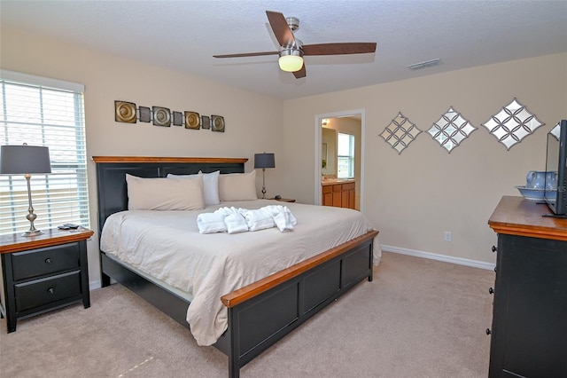 bedroom with visible vents, a ceiling fan, ensuite bath, baseboards, and light colored carpet