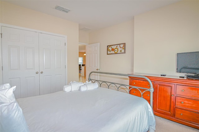 bedroom with a closet, visible vents, and light colored carpet