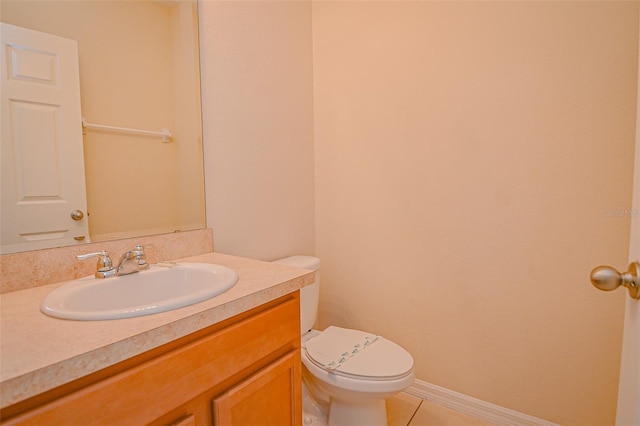 half bathroom with vanity, tile patterned floors, toilet, and baseboards