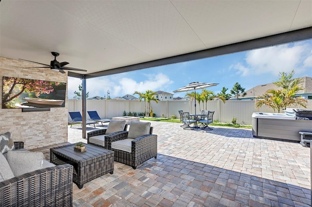 view of patio featuring a hot tub, ceiling fan, an outdoor hangout area, a fenced backyard, and outdoor dining space