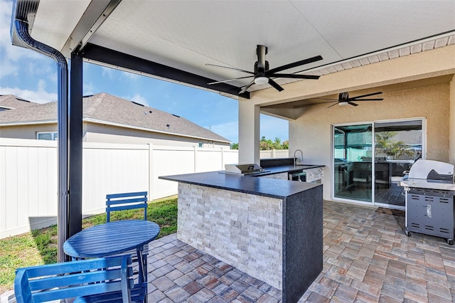 view of patio featuring a grill, exterior kitchen, a fenced backyard, and a sink