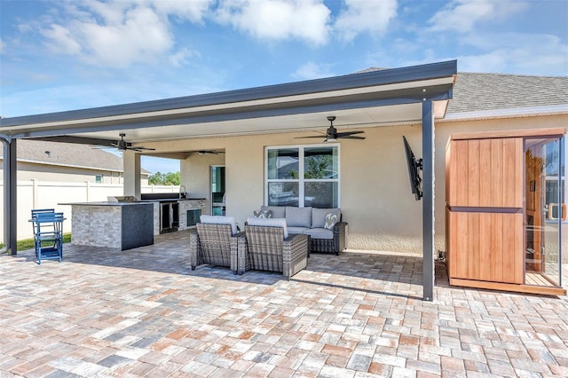 view of patio with a ceiling fan, beverage cooler, fence, an outdoor kitchen, and an outdoor living space