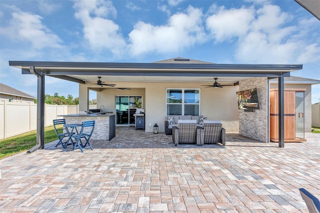 view of patio with an outdoor living space, an outdoor kitchen, a ceiling fan, and fence