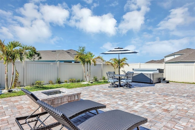 view of patio featuring outdoor dining space, a fenced backyard, and a hot tub