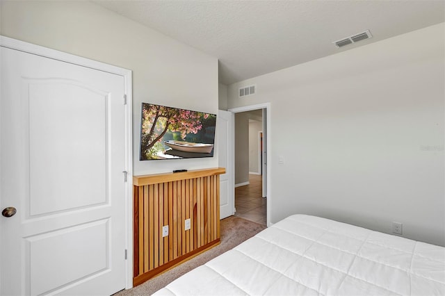 bedroom featuring visible vents, a textured ceiling, and carpet floors