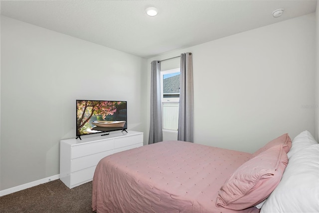 bedroom with dark colored carpet and baseboards