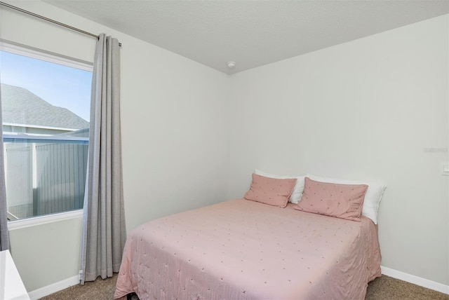 bedroom featuring carpet, baseboards, and a textured ceiling