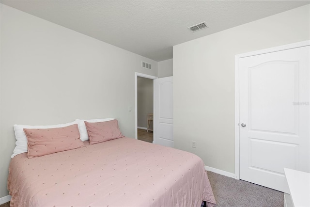 bedroom featuring visible vents, baseboards, carpet, and a textured ceiling