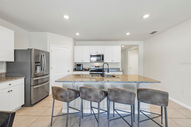 kitchen with a sink, visible vents, light stone counters, and appliances with stainless steel finishes