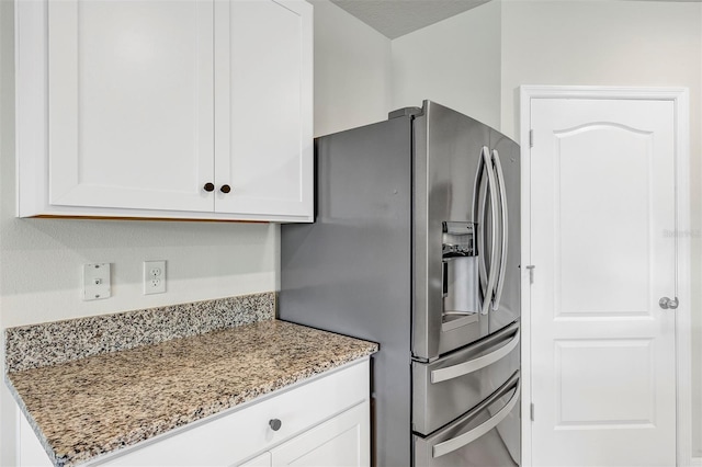 kitchen with white cabinetry, stainless steel refrigerator with ice dispenser, and light stone countertops