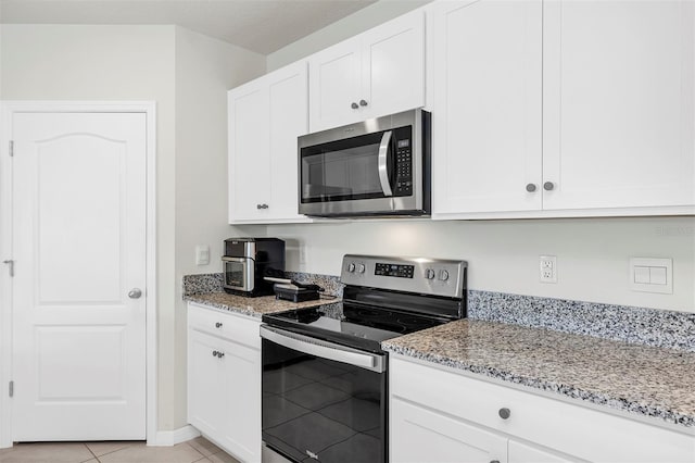 kitchen with white cabinetry, stainless steel appliances, and light stone countertops