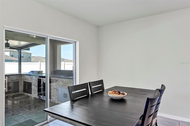 tiled dining space featuring beverage cooler and baseboards