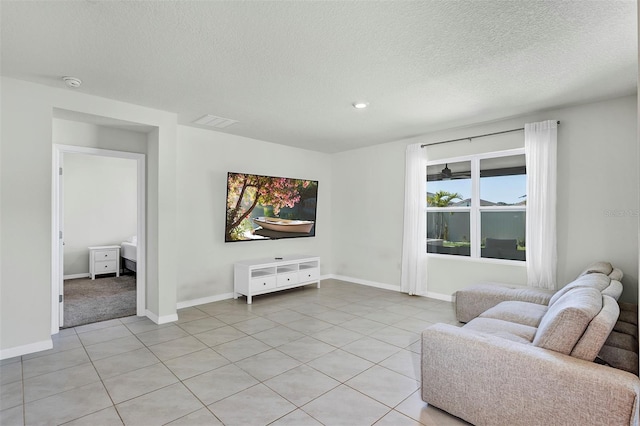 living area featuring light tile patterned floors, baseboards, and a textured ceiling