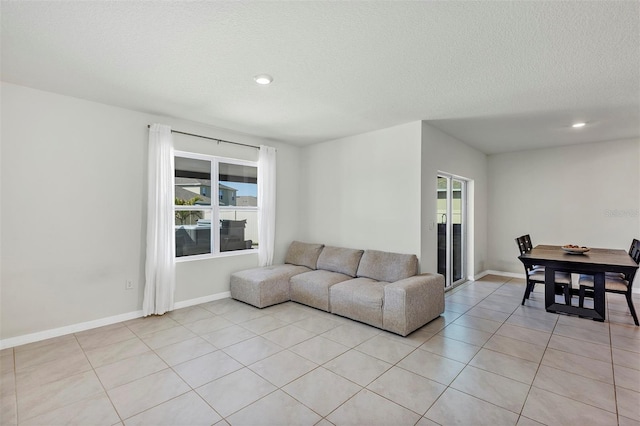 living room with light tile patterned floors, recessed lighting, a textured ceiling, and baseboards