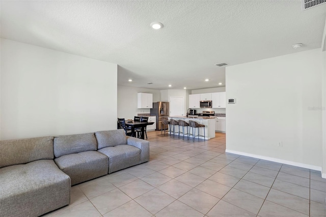 living area with recessed lighting, visible vents, and a textured ceiling