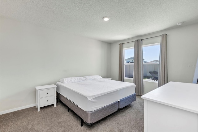 bedroom with light colored carpet, baseboards, and a textured ceiling