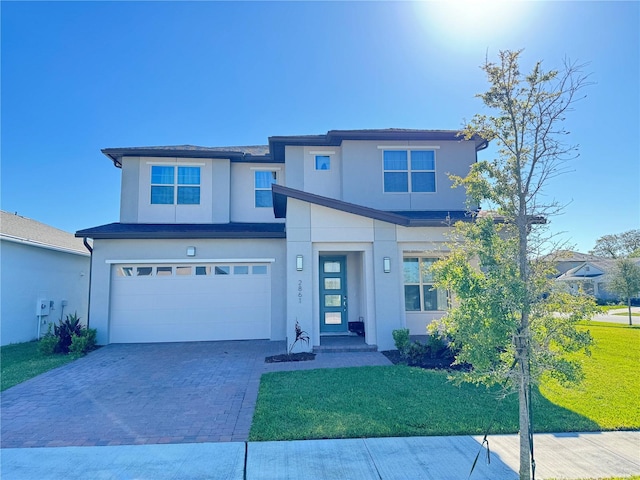 view of front of house with stucco siding, an attached garage, decorative driveway, and a front yard