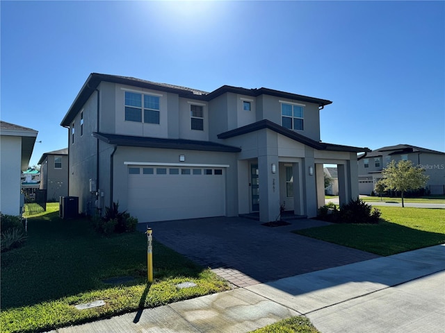 view of front of property with stucco siding, central air condition unit, a front yard, and an attached garage