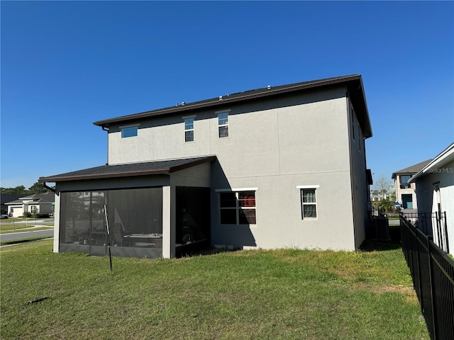 back of property with a lawn, fence, a sunroom, and stucco siding